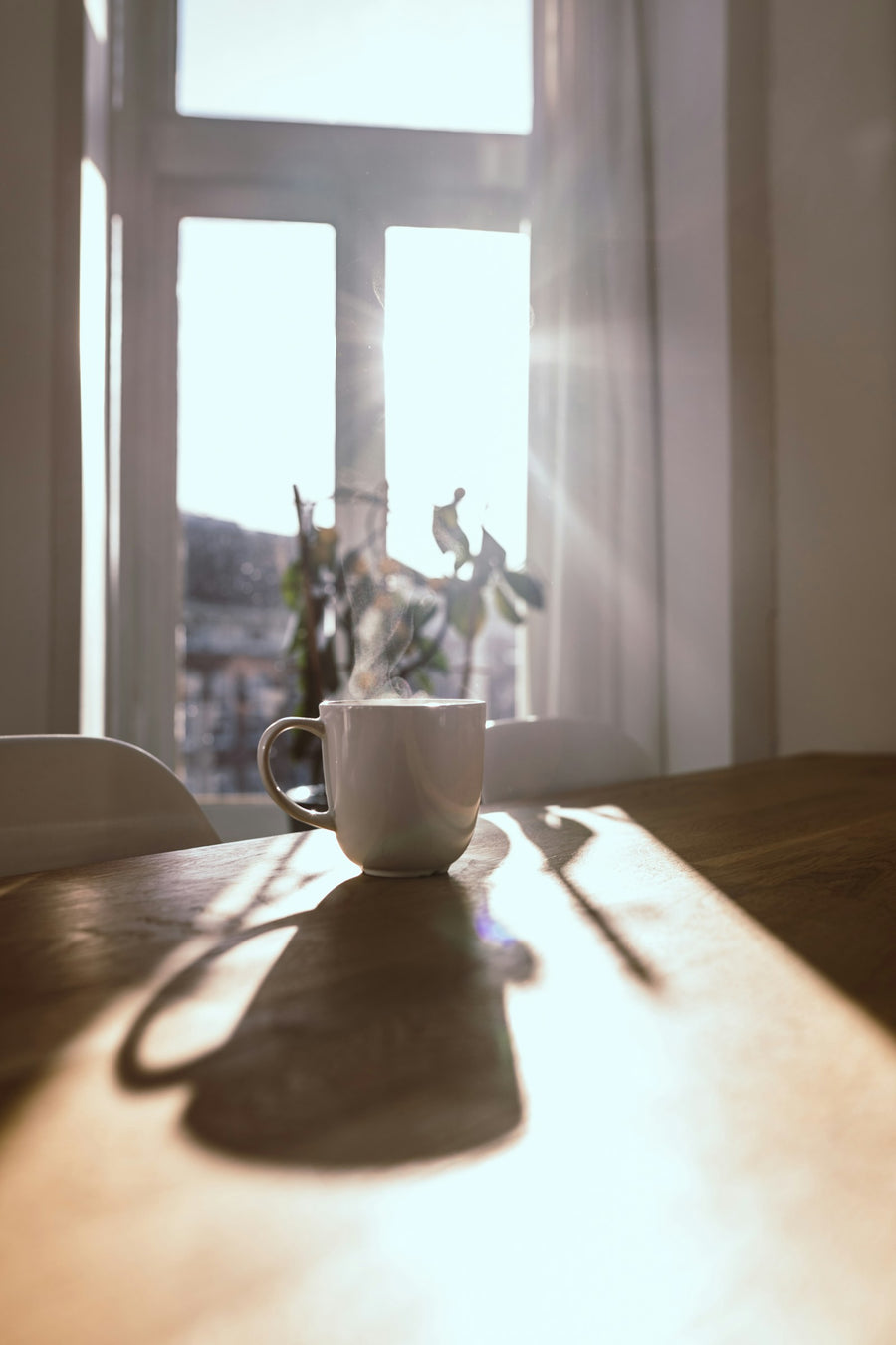 Taza humeante junto a una ventana con luz de la mañana